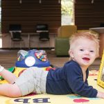 A toddler at Arlington Heights (Ill.) Memorial Library (AHML) enjoys tummy time while playing with Peek-a-Boo Mirror, a sensory toy in AHML’s collection.