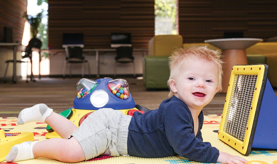 A toddler at Arlington Heights (Ill.) Memorial Library (AHML) enjoys tummy time while playing with Peek-a-Boo Mirror, a sensory toy in AHML’s collection.