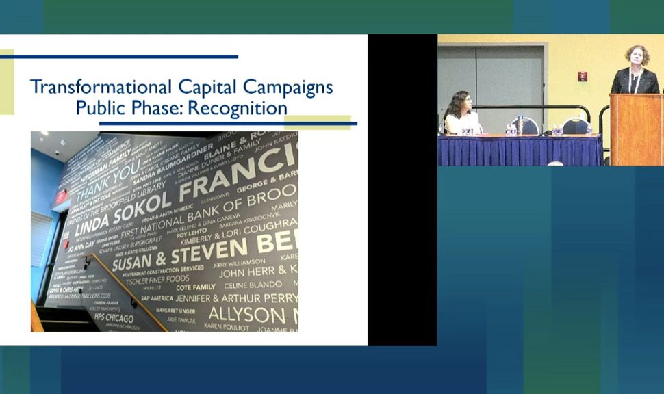 Screen cap of the presentation showing Linda Sokol Francis Brookfield Library's donor wall, with Kimberly Coughran (at podium) and Amanda McKay