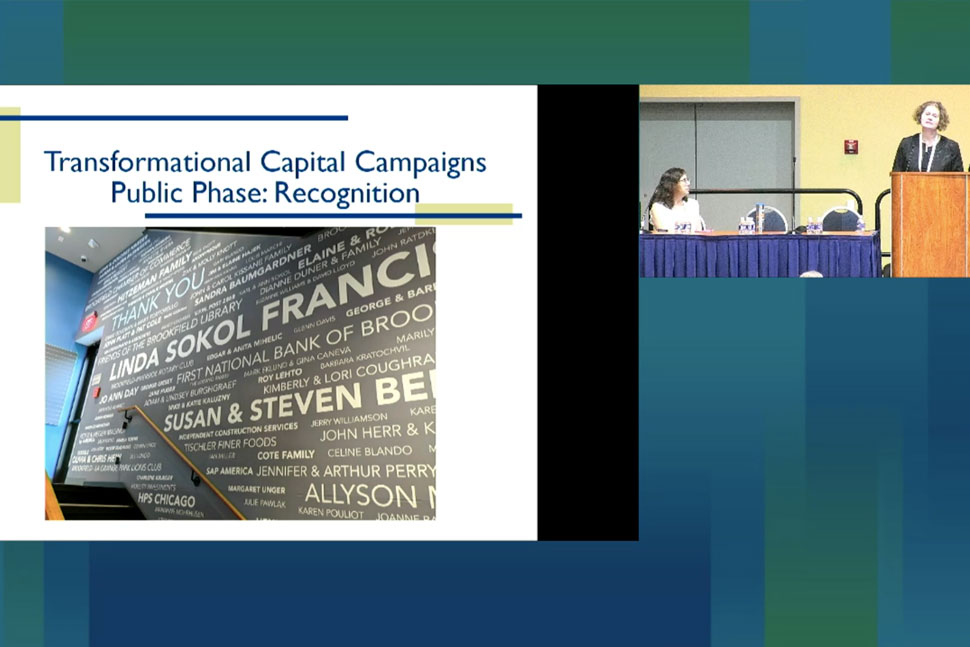 Screen cap of the presentation showing Linda Sokol Francis Brookfield Library's donor wall, with Kimberly Coughran (at podium) and Amanda McKay