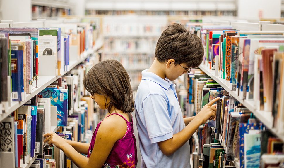 Two young children in a library aisle