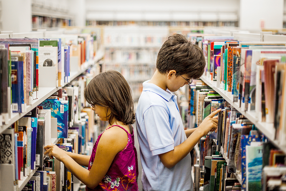 Two young children in a library aisle