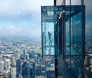 A figure standing in the Skydeck, an offste glass enclosure on the outside of Willis Tower