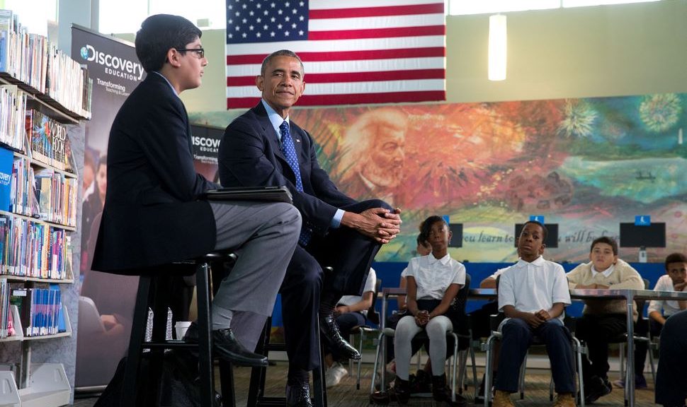 President Barack Obama at Washington, D.C.'s Anacostia Neighborhood Library, being interviewed by a sixth-grade student while other students look on.