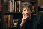 Neil Gaiman in front of a bookshelf
