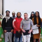 Eight people standing with certificates in their hands