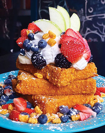 Stack of french toast topped with fruit and whipped cream