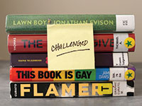 A stack of frequently challenged and banned books with a post-it over them that reads "challenged"