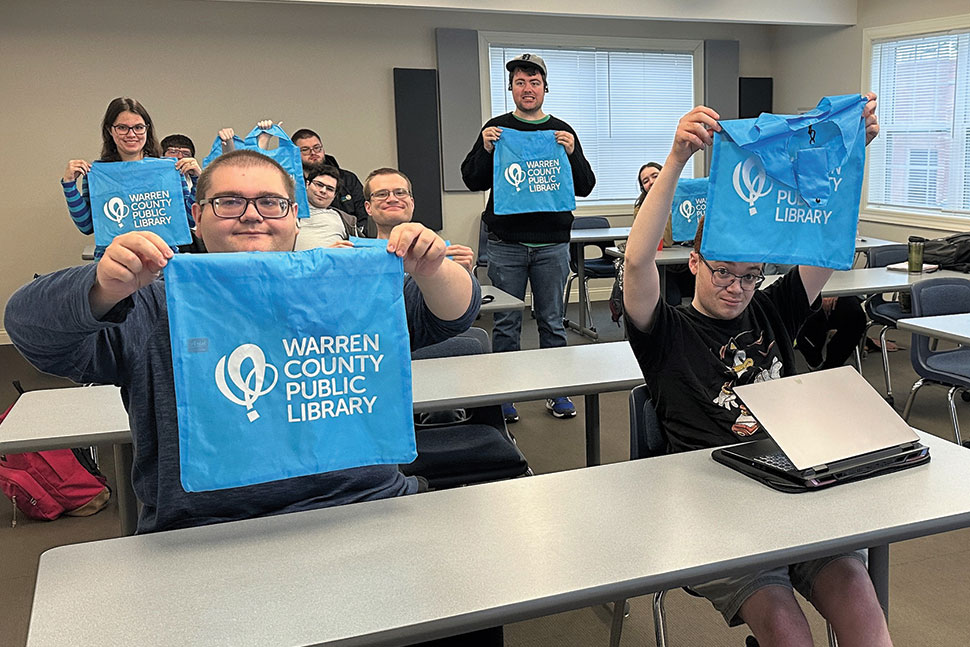 Participants at LifeWorks, a residential community for neurodiverse young adults, hold bags from Warren County (Ky.) Public Library (WCPL). WCPL recently opened a satellite branch at LifeWorks.