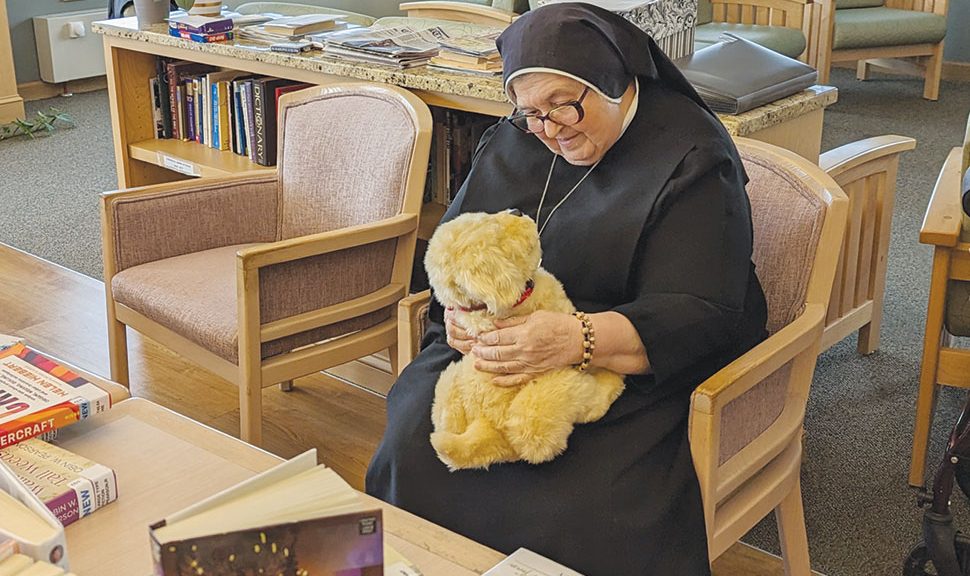 Sister Stella, a resident of Queen of Peace, a retirement community for nuns, plays with Henry. The robotic dog belongs to Ela Area Public Library in Lake Zurich, Illinois.