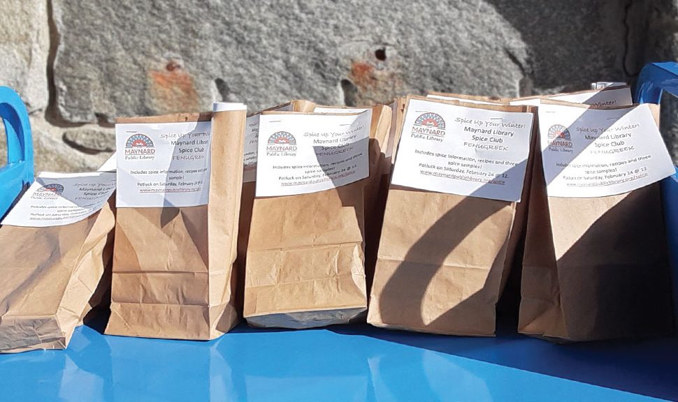 Image shows a row of paper bags filled with Maynard (Mass.) Public Library's February spice of the month, fenugreek.