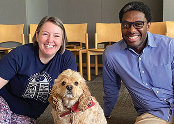 Oak Park (Ill.) Public Library (OPPL) staffers Jenna Friebel (left) and Stephen Jackson pose with a therapy dog. OPPL brings in dogs quarterly as part of a plan to boost staff wellness. 