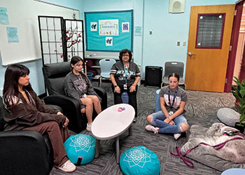 Diana Haneski (center), library media specialist at Marjory Stoneman Douglas High School in Parkland, Florida, and students meditate alongside River, the school library’s therapy dog