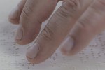 Close up of a hand reading a Braille document