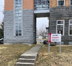 An outdoor sign that reads "Canadian entrance" in English and French features a red arrow pointing toward an emergency-exit door to the library.