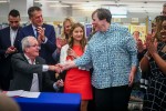 Martha Hickson, a recently retired media specialist who fought censorship at North Hunterdon High School in Annandale, New Jersey, shakes hands with New Jersey Gov. Phil Murphy (seated) after he signed into law last winter a measure to limit book bans and protect librarians from liability in the state. <span class="credit">Photo: Dana DiFilippo/New Jersey Monitor</span>