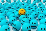 One ball with a smiley emoji in a field of frowny emoji balls.
