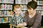 Student being aided by a teacher in a library.
