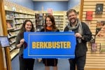 Librarians at Berkley (Mich.) Public Library holding a "Berkbuster" sign in front of the library's Blockbuster-themed video section