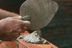 Close-up of a trowel spreading mortar on an under-construction brick wall