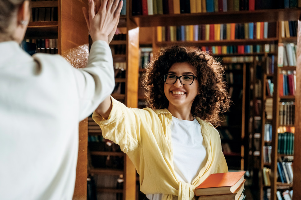 An image of a woman high-fiving another person in the library