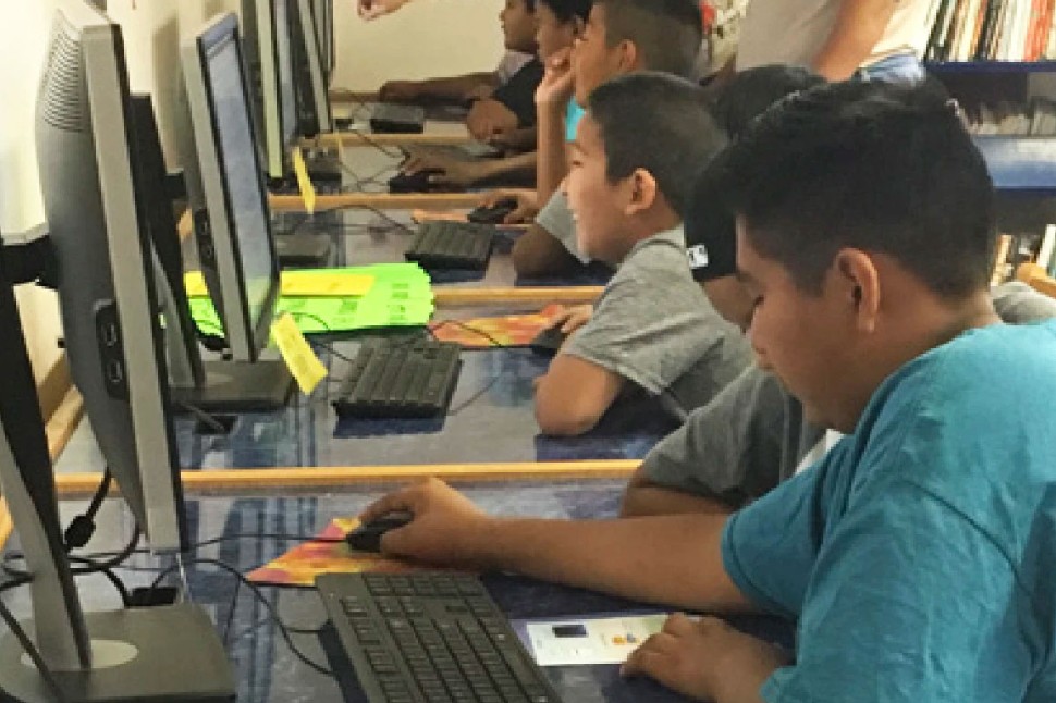 Several children using computers in a library