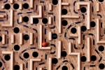 Marble running through a wooden labyrinth with numerous holes