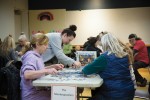 Group of people assembling a jigsaw puzzle at a speed puzzling competition.