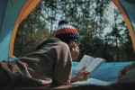 Woman reading in a tent while camping