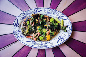 A plate of whole fish with herb salad.