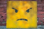 Angry smiley cartoon against a brick wall